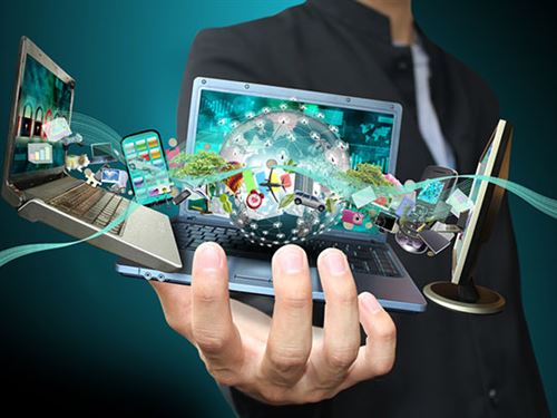 Hand holding laptops with colorful images bursting from screens
